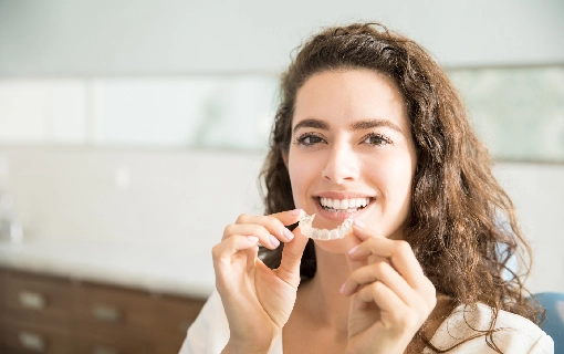 Women Smiling while holding Invisalign